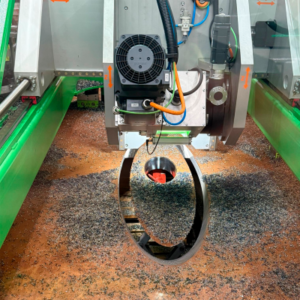 Close-up view of CNC Onsite's gantry millling machine head cutting a precise 45 degree angled cable penetration hole at a transition piece into a metal surface covered in metal shavings